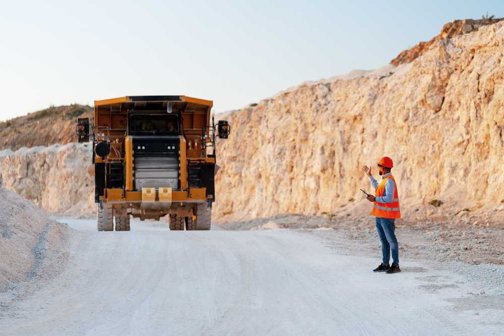 Mining,Engineer,Holding,A,Tablet,While,Directing,A,Dumper,Truck Mining site operation